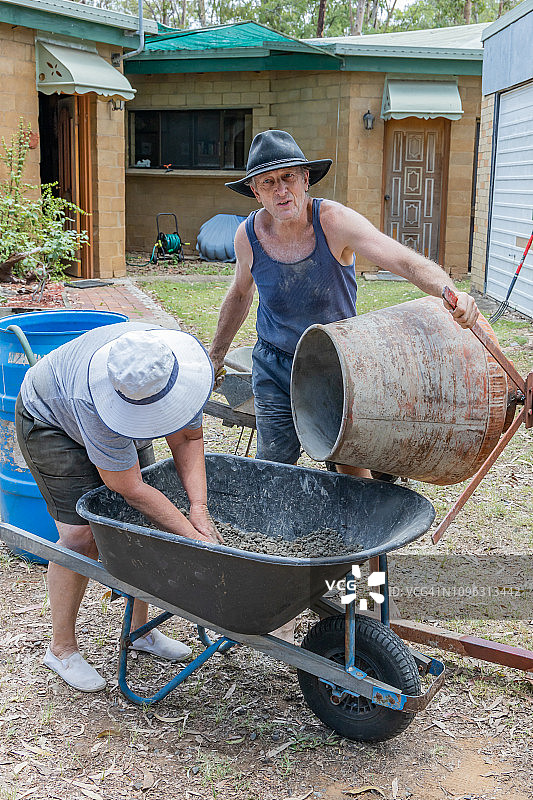 一起制作自制砖的夫妇：在混凝土搅拌机中准备砖块混合物图片素材