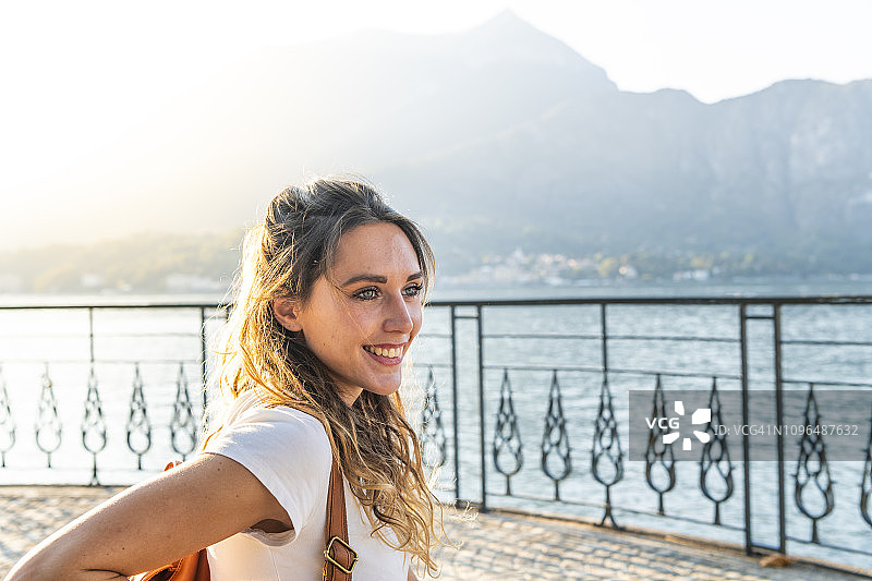 一位快乐的年轻女子在日落时分在湖边微笑图片素材