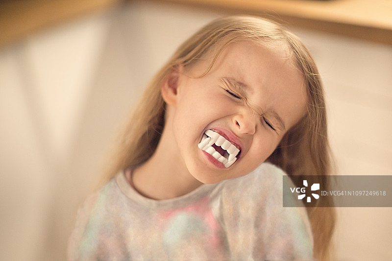 6-7岁儿童戴着假吸血鬼牙齿并做鬼脸图片素材