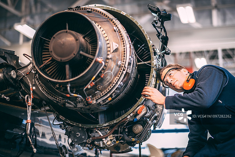 飞机工程师在维修机库中维修和维护小型飞机的喷气发动机图片素材