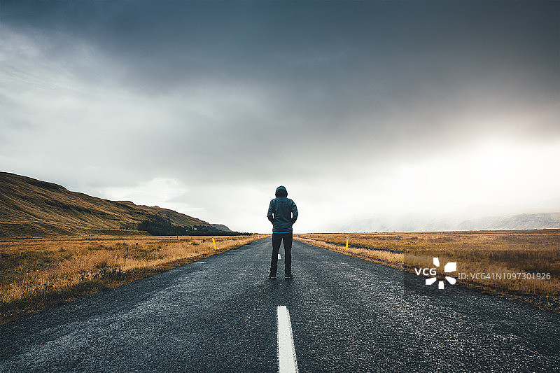 男子站在冰岛的道路中央图片素材