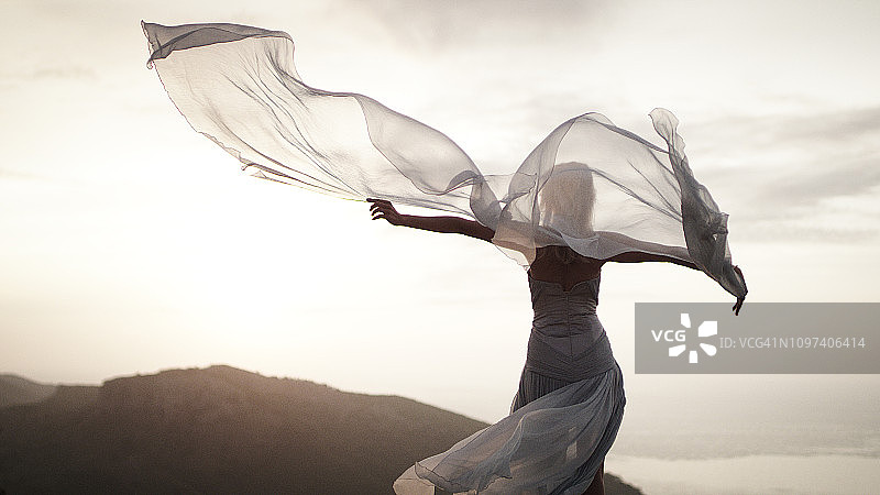 迎风。身穿优雅礼服的女子在山中摆姿势图片素材