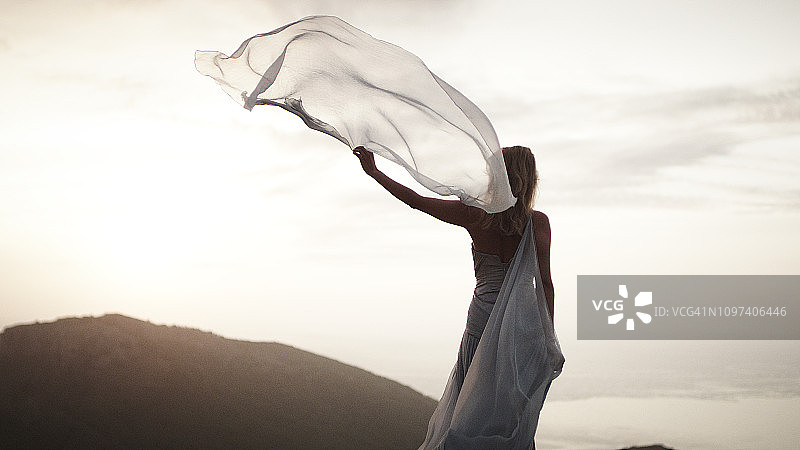 迎风。身穿优雅礼服的女子在山中摆姿势图片素材