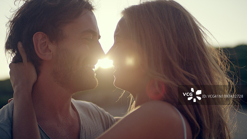 情侣在海滩上依偎站立日落图片素材