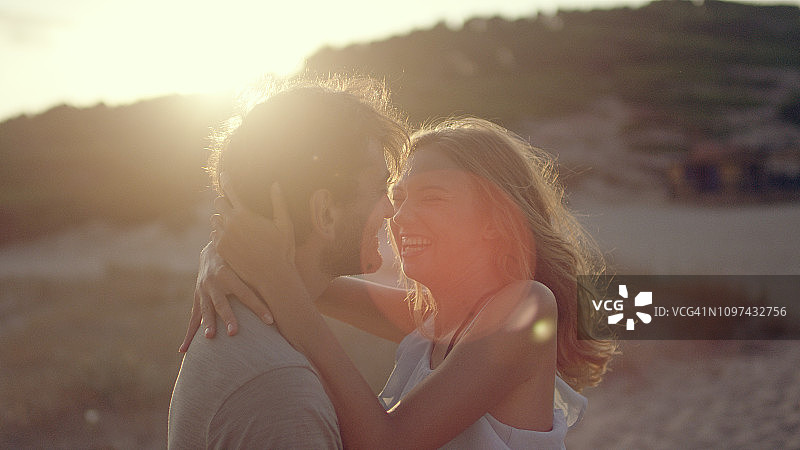 情侣在海滩上依偎站立日落图片素材