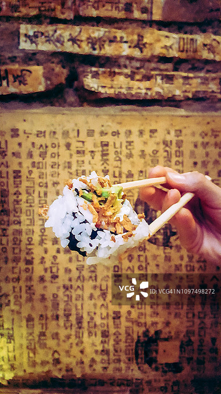 女人用筷子夹着寿司卷图片素材