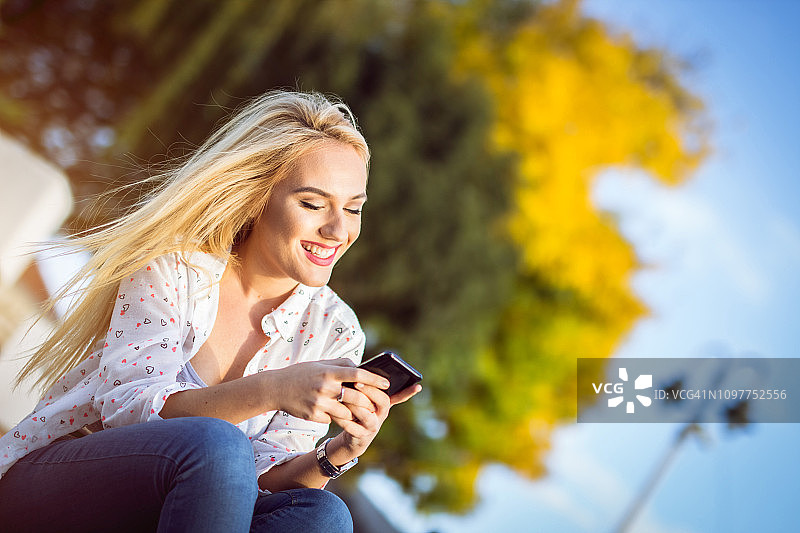 金发女孩在公园用手机图片素材
