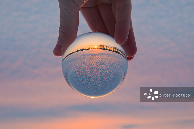 手持水晶球，内含冬季日落特写图片素材