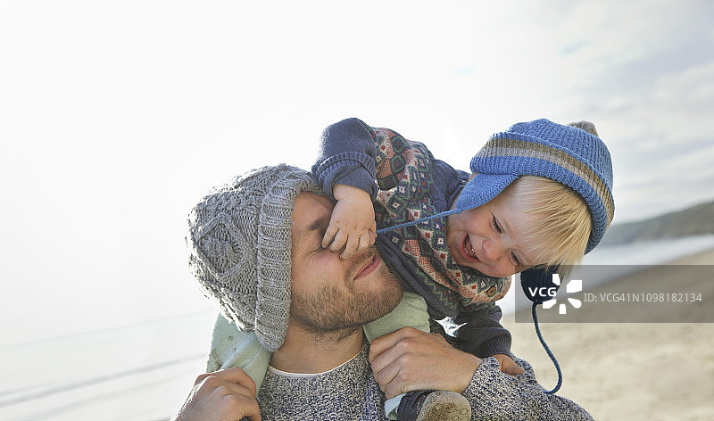 年轻的父亲在海滩上背着幼儿图片素材