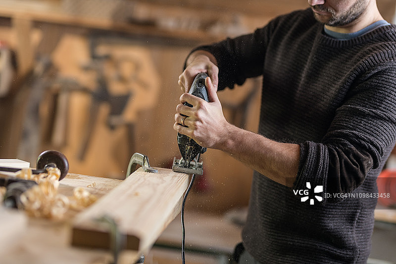 使用电动砂光机的年轻木匠图片素材
