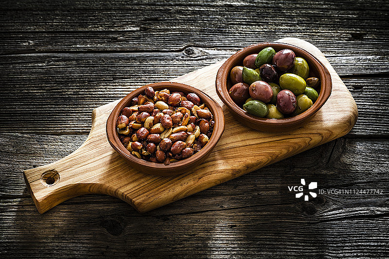 乡村木桌上的粘土碗里的橄榄和花生图片素材