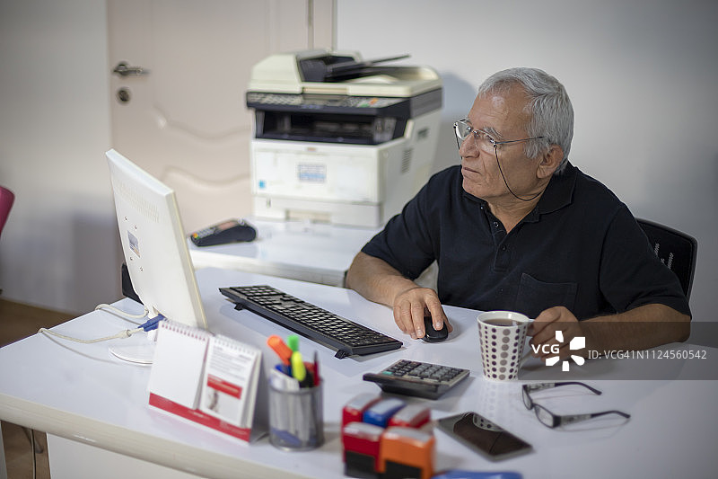 老年男人在办公室的桌子上使用电脑图片素材