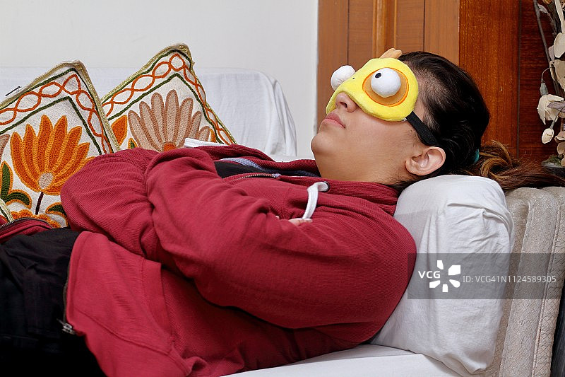 少女戴着睡眠眼罩在沙发上睡觉图片素材