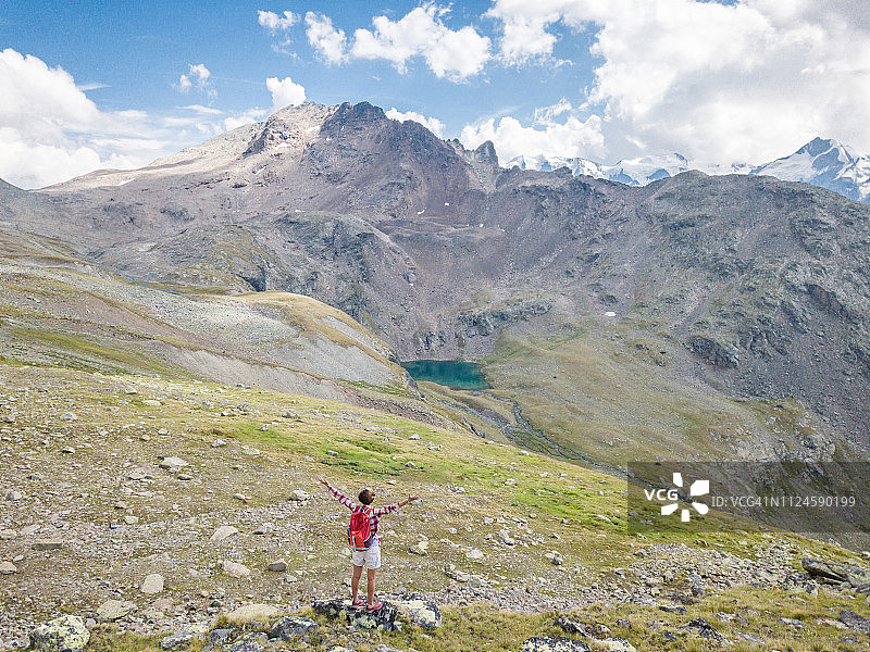 无人机视角：徒步女性站在山顶伸开双臂，象征着登上顶峰的成功图片素材