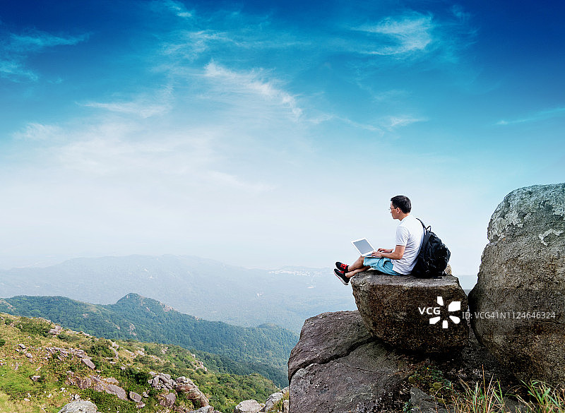 在山顶使用笔记本电脑的男人图片素材