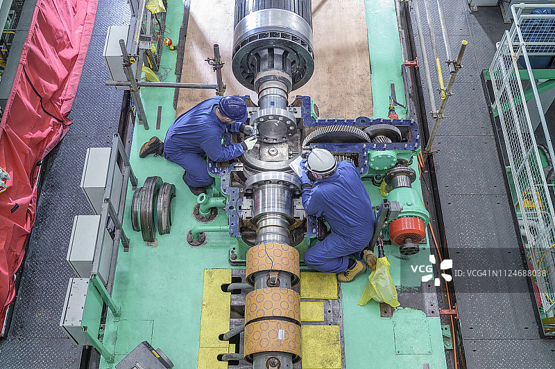 核电站汽轮机大厅内工程师检查发电机齿轮俯视图图片素材