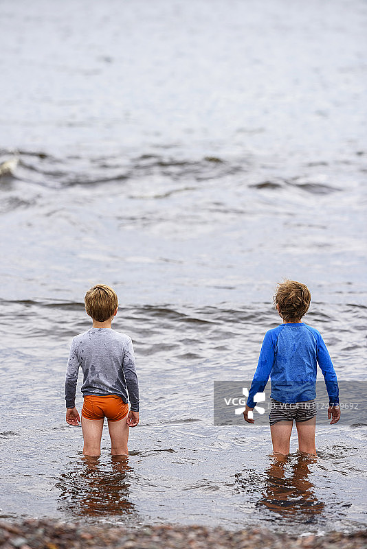 两个男孩站在美国的海里，水深及膝图片素材
