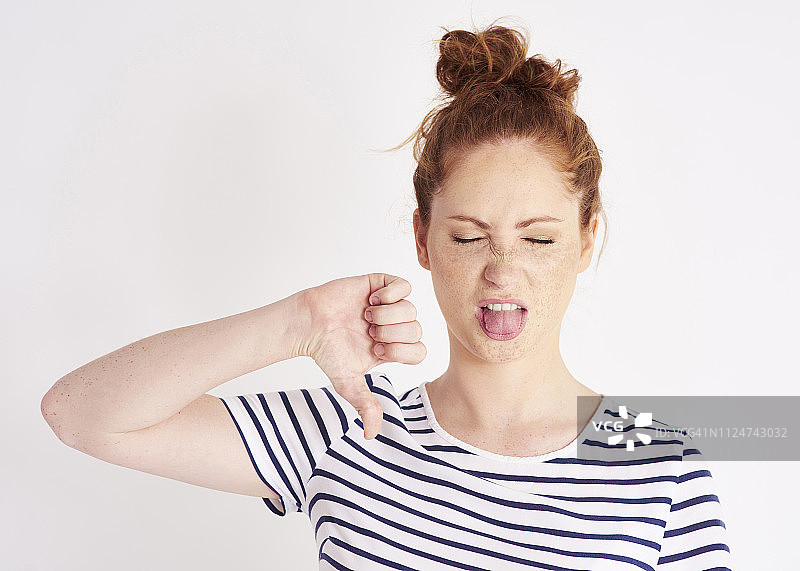 在演播室拍摄中，女人做出拇指向下的手势并扮鬼脸图片素材