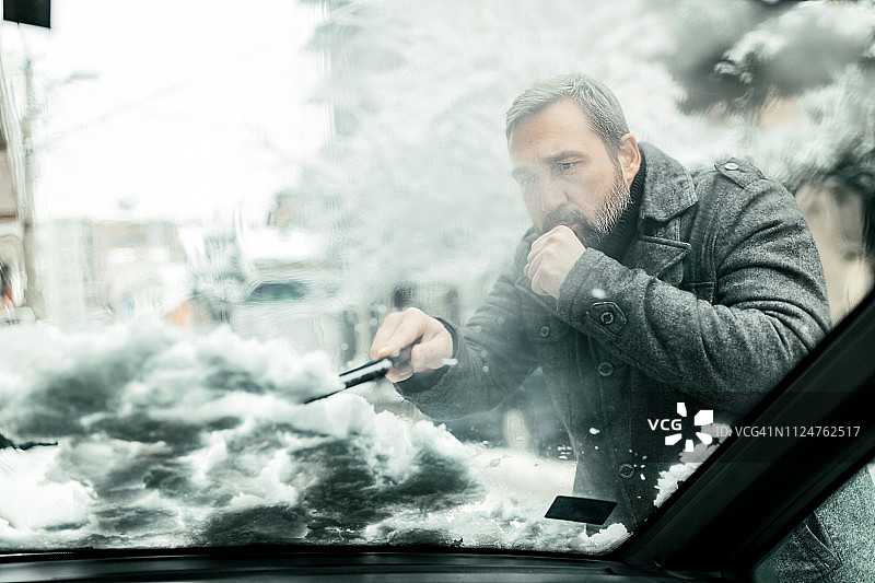 男人清除汽车上的积雪图片素材