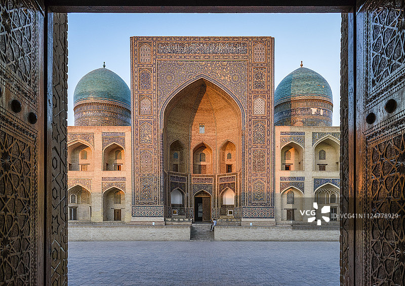 布哈拉市中心一所伊斯兰学校或清真寺的庭院、装饰拱门和尖塔景观图片素材
