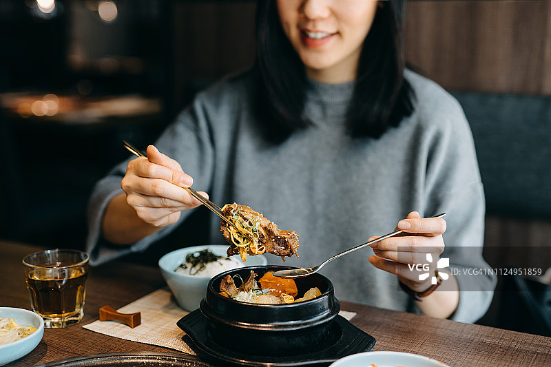 微笑的年轻亚洲女子在韩国餐厅享用韩国料理图片素材