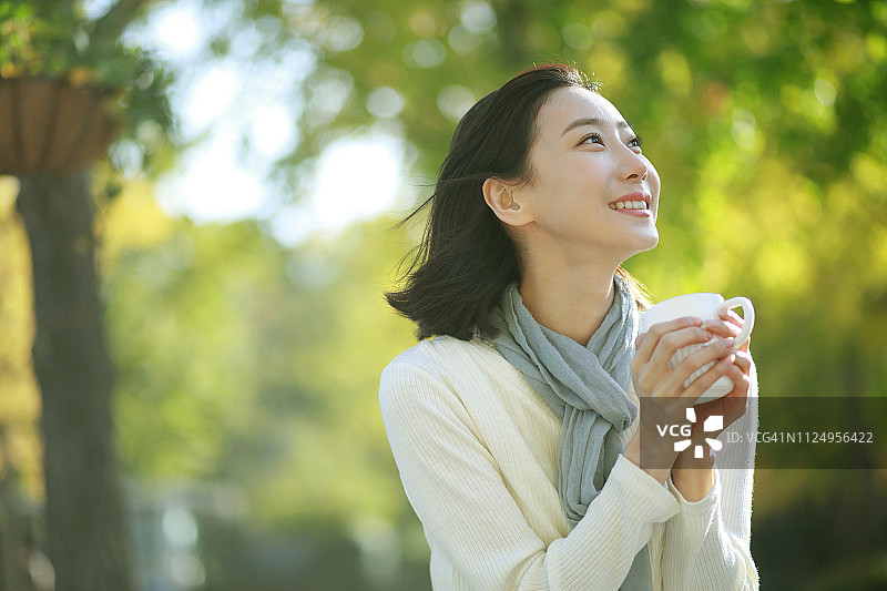 年轻女人在公园里喝咖啡图片素材