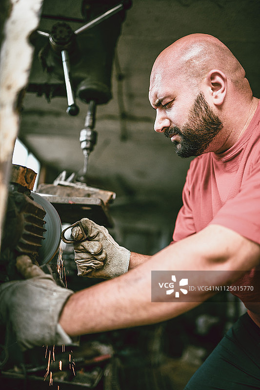 修理机器零件的秃头男修理工图片素材