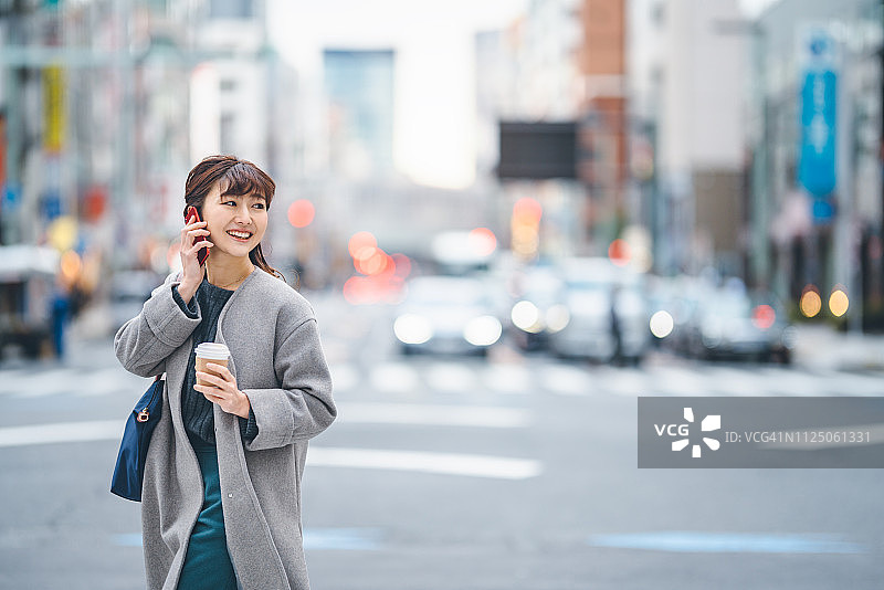 女商人边打电话边过马路，手里拿着咖啡图片素材
