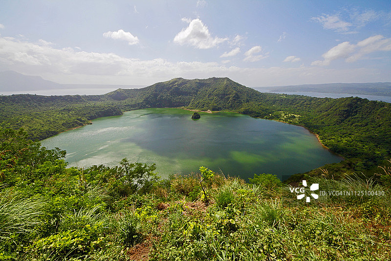 塔尔火山的火山口，周围环绕着茂密的绿色植物图片素材