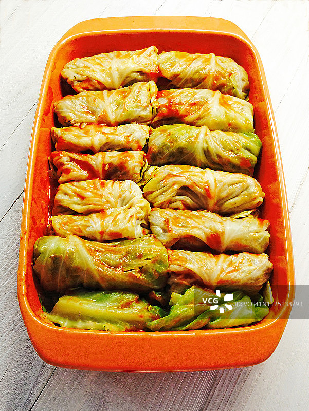 白色木质背景烤盘中卷起来的酿卷心菜图片素材