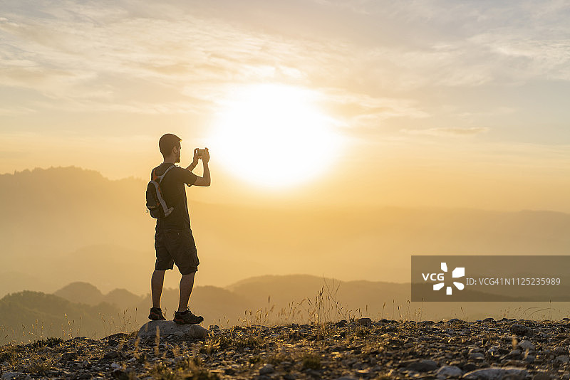 西班牙巴塞罗那圣劳伦茨自然公园，日落时分男人徒步拍照图片素材