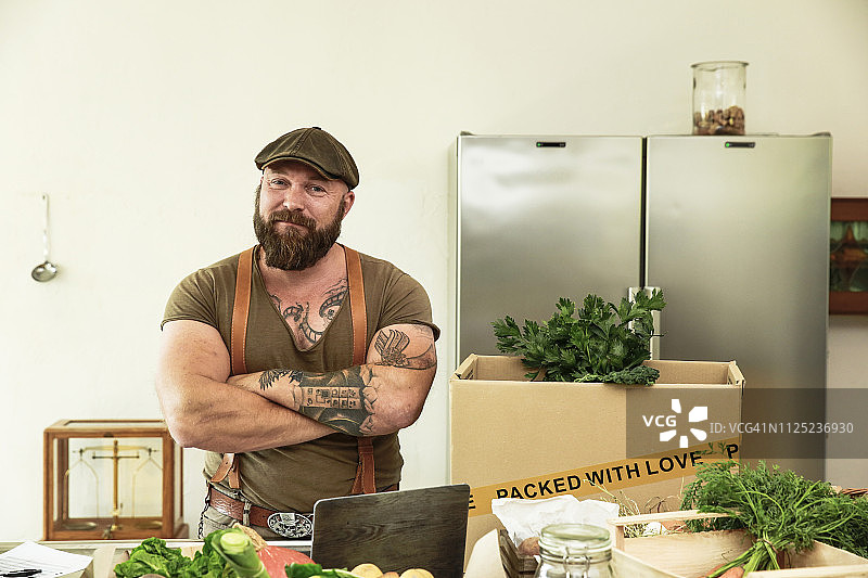 一家有机蔬菜配送服务的店主，自豪地站在厨房里图片素材