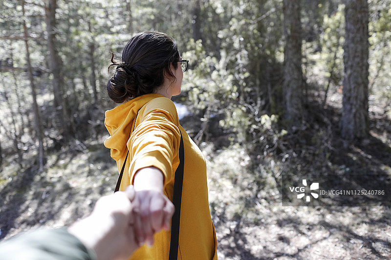 身穿黄色毛衣的年轻女孩牵着森林里男人的手图片素材