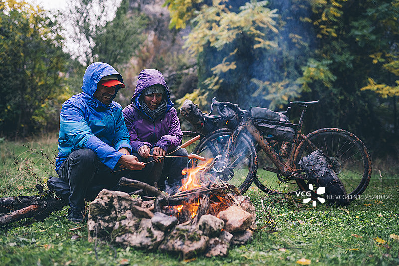 情侣在篝火旁烤香肠，骑着BMX自行车欢笑图片素材