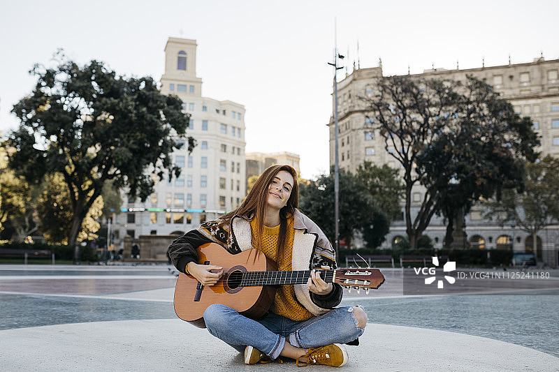 红发女子在城市里弹吉他图片素材
