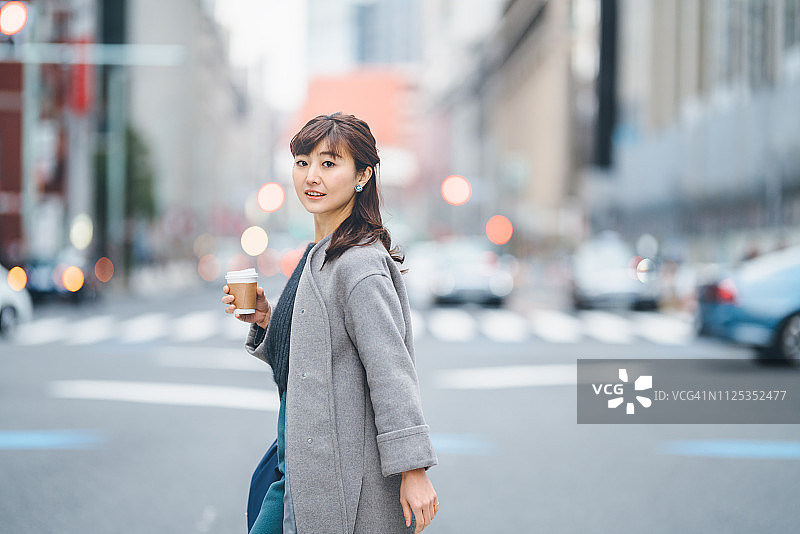拿着咖啡过马路的商务女人图片素材