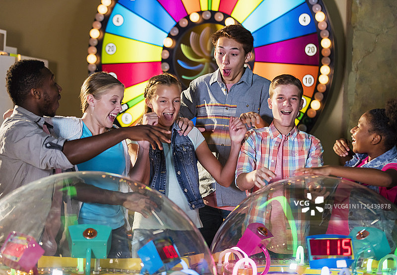 多元种族青少年朋友玩街机游戏图片素材