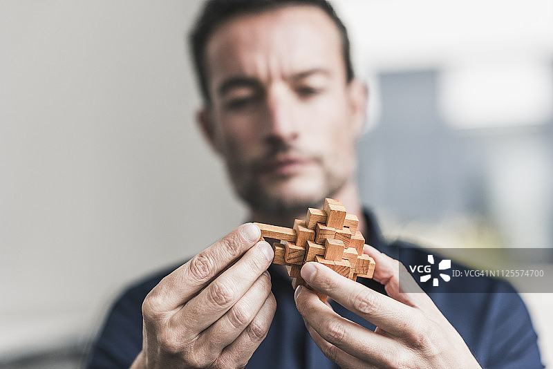 坐在办公室组装木制魔方拼图的中年男人图片素材