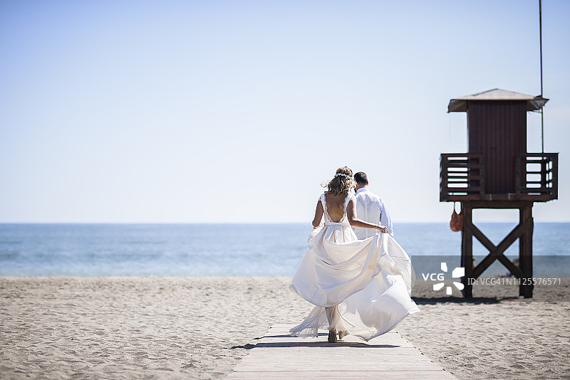 新婚夫妇在沙滩上享受婚礼（背影）图片素材