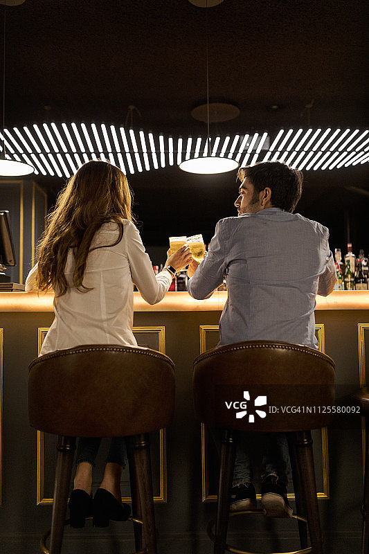 情侣在酒吧碰啤酒杯（背面视角）图片素材