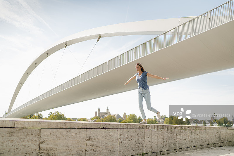 荷兰马斯特里赫特在桥上墙上保持平衡的年轻女子图片素材