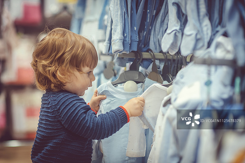 购物时选择蓝色衣服的可爱小男孩图片素材