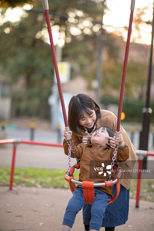 年轻母亲和小儿子在公园里荡秋千图片素材