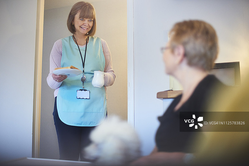 快乐的家庭护理人员为年长的女人带午餐图片素材