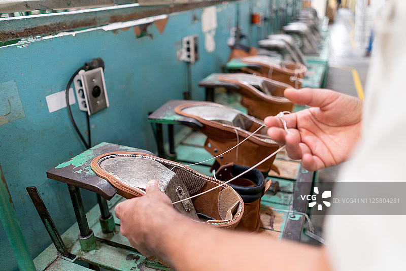 生产线上缝制靴子的男人的特写镜头图片素材