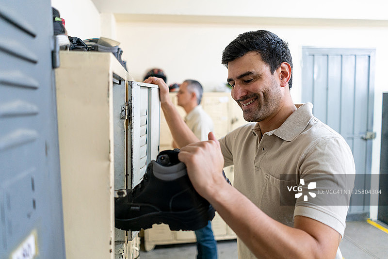 准备工作的拉丁美洲英俊男子从储物柜里拿出工作靴图片素材