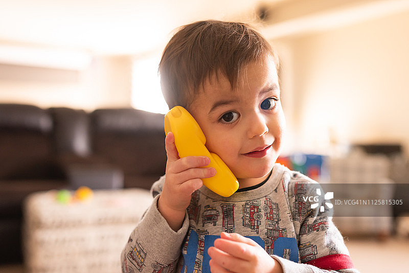 幼儿拿着复古玩具电话听筒，背光拍摄于地下室图片素材