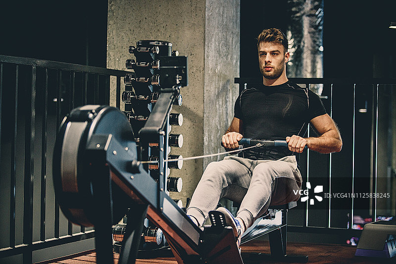专注的运动员在划船机上锻炼图片素材