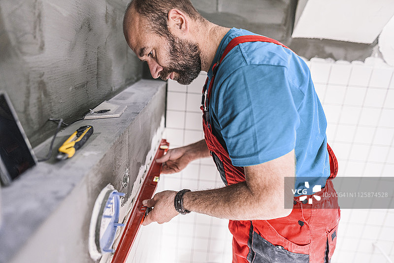 瓦工在安装瓷砖时找平浴室墙壁图片素材
