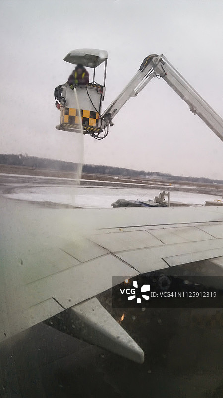 机场工作人员为准备起飞的飞机进行除冰作业，喷射防冰液图片素材